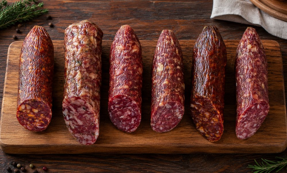 Assorted dry cured hog casing salami sliced on wooden board